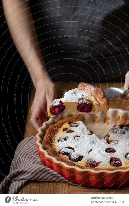 Crop cook with piece of cherry clafoutis on knife cake person tasty baked pastry delicious homemade wooden table stand dessert food sweet bakery gourmet fresh