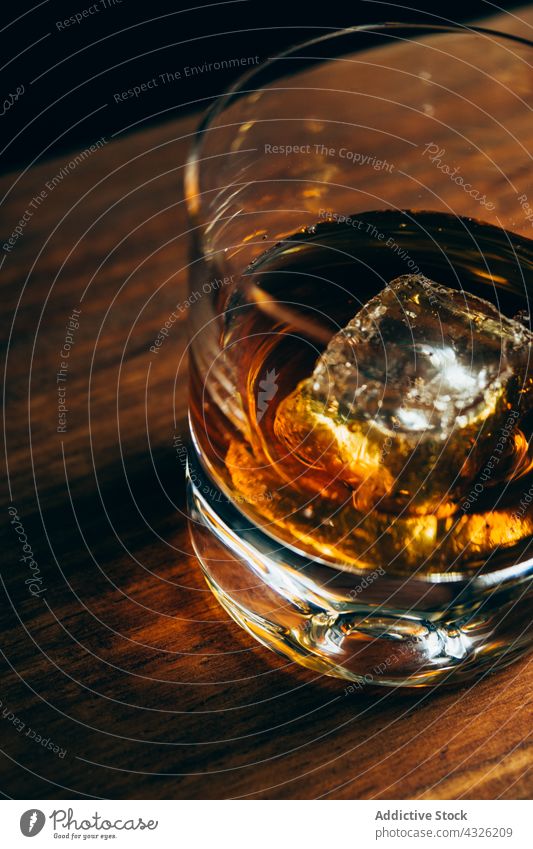 Glass with whiskey and ice glass table cup cold drink alcohol dark cube crystal container beverage liquid cool booze lumber timber wooden party luxury elegant