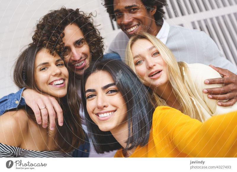 Multi-ethnic group of friends taking a selfie together while having fun outdoors. people smartphone multiracial multi-ethnic persian arab students photographing