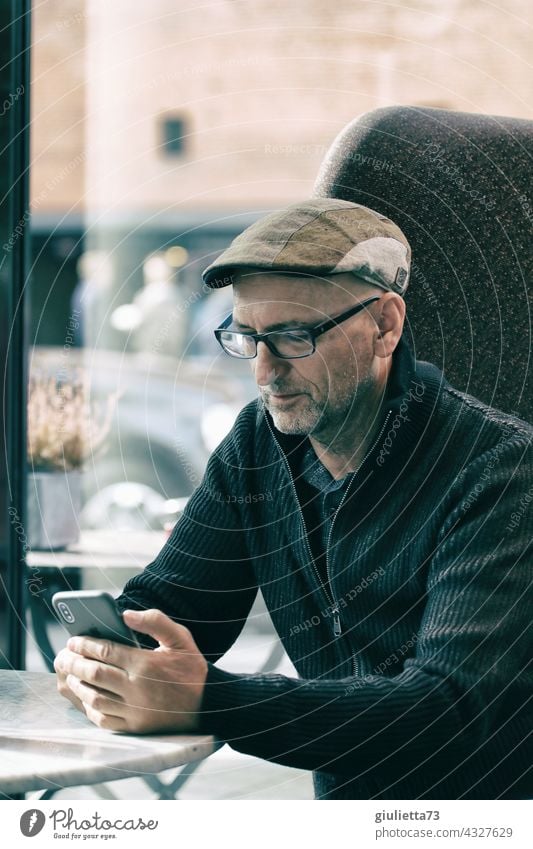 Lonely man with glasses sits in a café and looks at his mobile phone | UT HH 19 Male senior Masculine Man Adults Human being 45 - 60 years Life Eyeglasses Hope