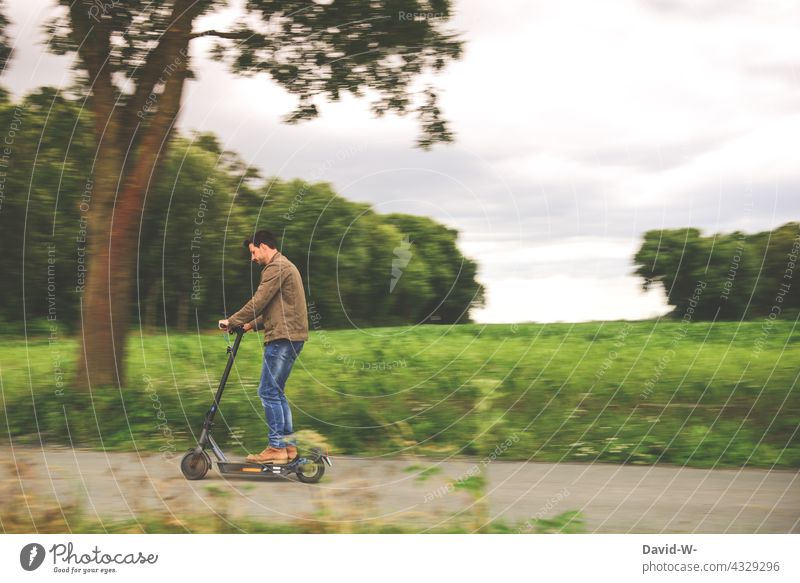 Man riding an e-scooter e-roller Driving Nature outside Modern electric scooter Future Street Lifestyle