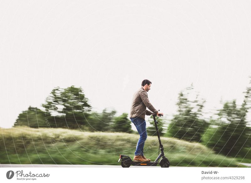 Man on the road with e-scooter e-roller Driving more eroller Nature Street Mobile Sustainability Modern Speed Electric electric scooter