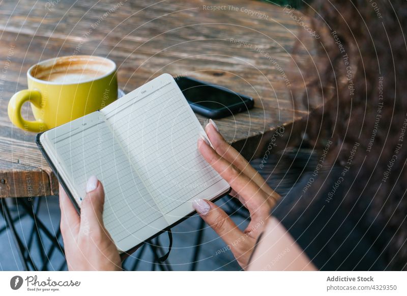 Woman flipping notebook in cafe woman coffee page read planner empty entrepreneur busy female work terrace cup freelance businesswoman lifestyle occupation