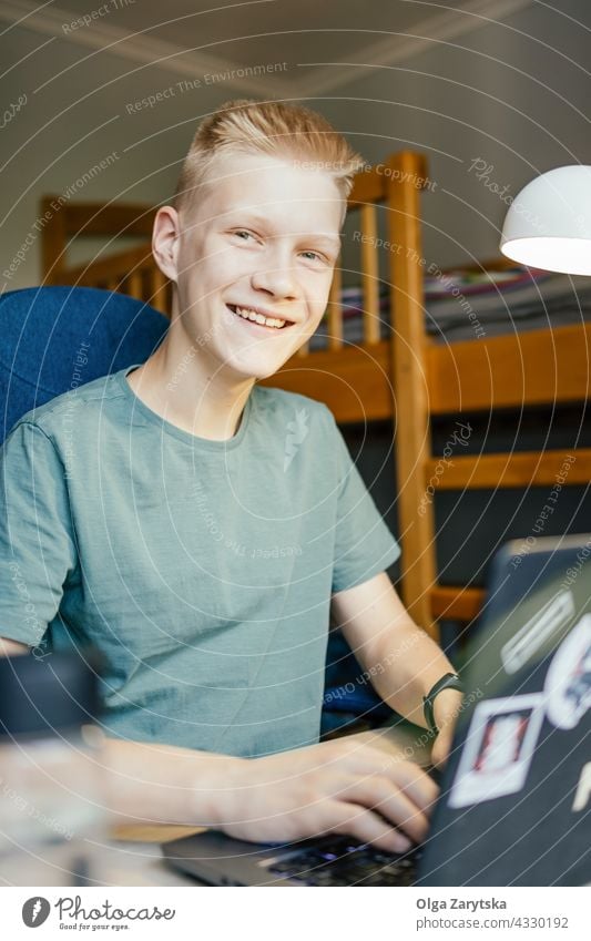 Young man smiling and looking at camera. student working online young home dormitory programmer education college studying laptop boy teenager 14-15 caucasian