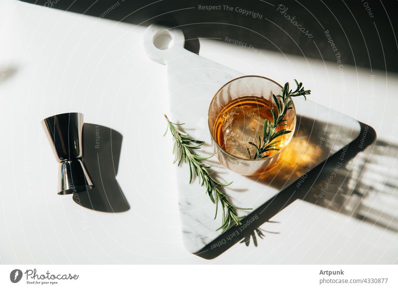 whiskey with rosemary garnish cocktail afternoon light Bourbon liquor marble kitchen scotch glass