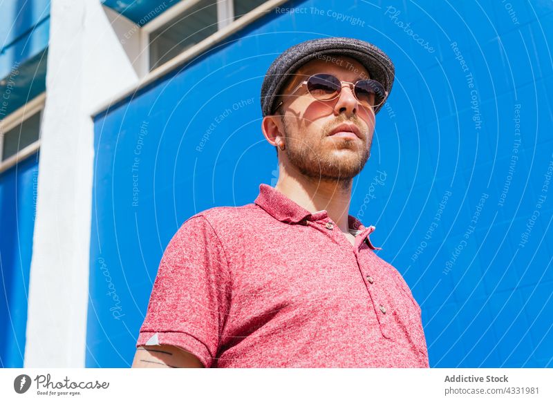 Man in trendy outfit and sunglasses on blue background man style summer beard urban male young modern hipster friendly handsome polo eyeglasses eyewear guy