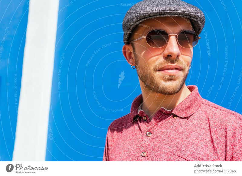 Man in trendy outfit and sunglasses on blue background man style summer beard urban male young modern hipster friendly handsome polo eyeglasses eyewear guy