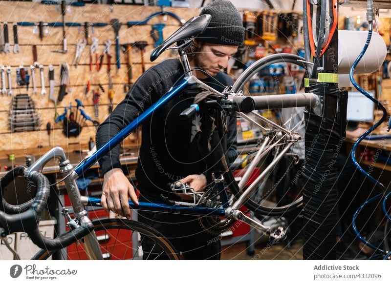Focused man fixing bike in garage bicycle wheel workshop repair mechanic repairman male service vehicle job professional transport busy tool maintenance