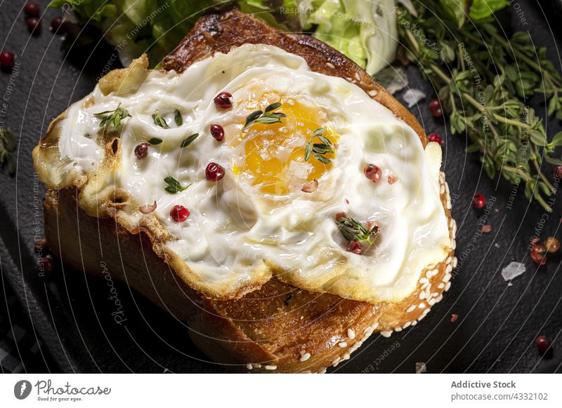 Fried egg on brioche with lettuce on black tray fried breakfast appetizing nutrition serve plate table food delicious meal dish green thyme portion palatable