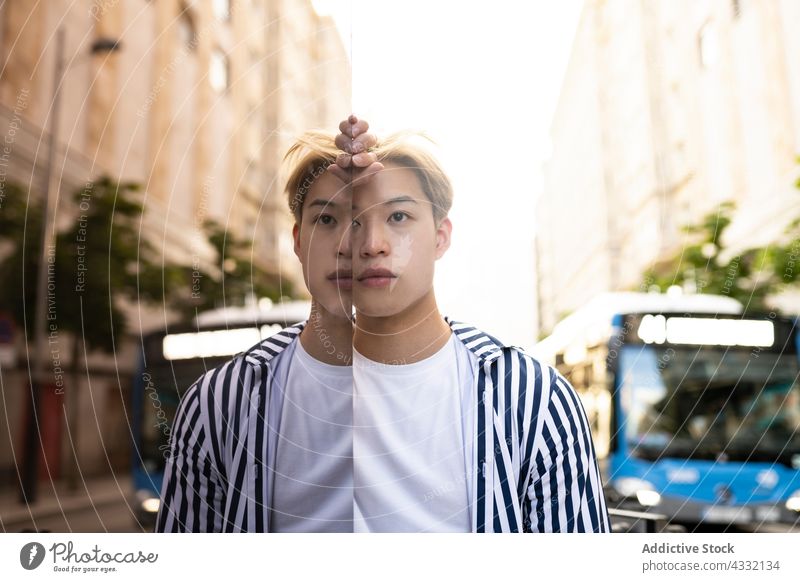 Asian man standing near glass wall in city model reflection mirror street style confident male ethnic asian fashion outfit urban blond trendy building lean