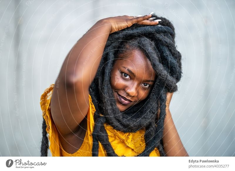 Beautiful young woman with dreadlocks in front of gray wall proud real people city life African american afro american Black ethnicity sunny sunset outside girl