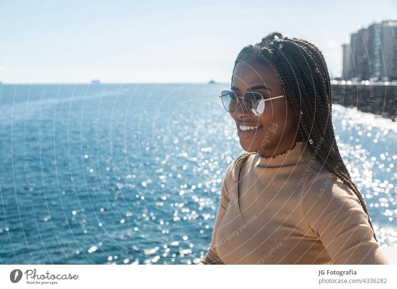 Portrait of young black girl smiling with blue sea background woman lifestyle people afro sky happy outdoors adult casual attire urban beautiful person female