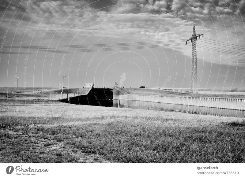 Dike with lock in Oldersum Floodgate Ems East Frisland Northern Germany Meadow Exterior shot Lower Saxony Electricity pylon High voltage power line Deserted