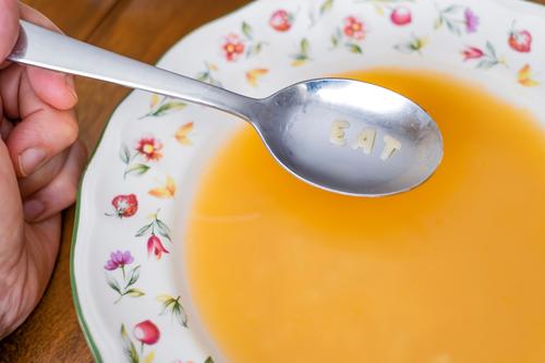 eat message on a spoon on a bowl of alphabet soup on a wooden table dish plate eating letters food text pasta concept cook fun epicure noodle note wheat diet