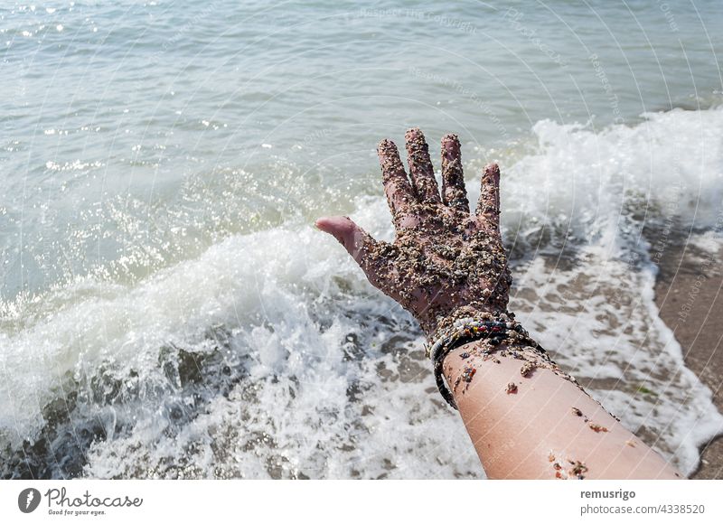 Hand covered with sand adult beach body bracelet caucasian coastline female fingers foam hand holiday human island nature ocean outdoors part people person sea