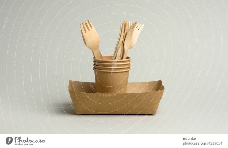 disposable brown paper cups, rectangular plates and wooden forks on a gray background biodegradable cardboard catering concept container craft cutlery dining