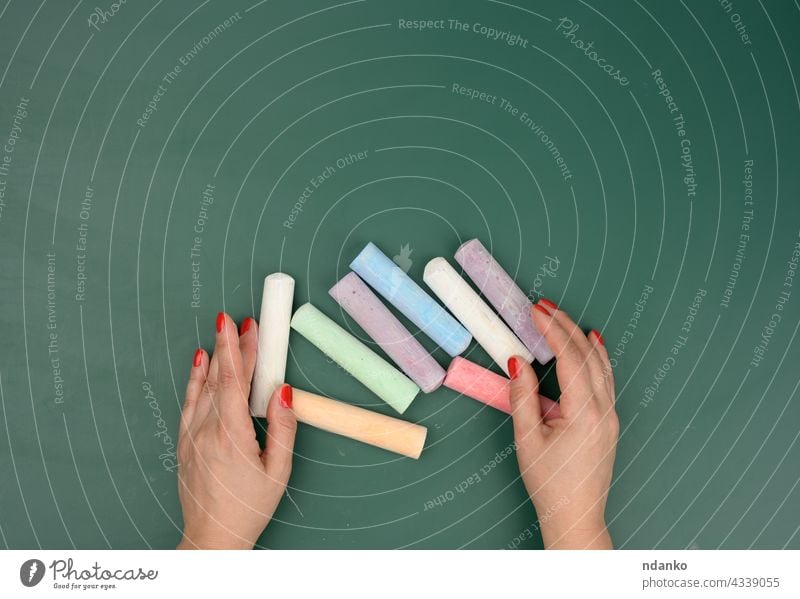 hand holds a piece of white chalk on the background of an empty green chalk board adult advertisement blank caucasian chalkboard childhood classroom closeup