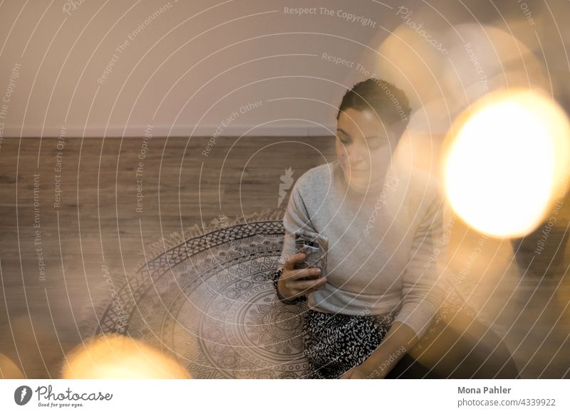 Young woman in warm atmosphere with lights stares at her mobile phone smartphone Woman Technology Telephone hands Internet using Mobile Modern Lifestyle