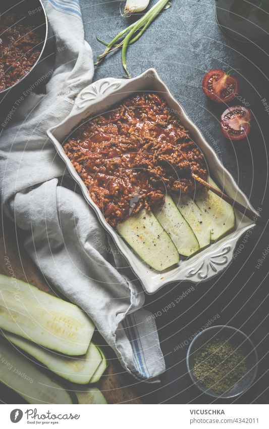 Cooking preparation of zucchini lasagne bolognese on dark kitchen table with ingredients. Healthy dieting food. Top view cooking healthy top view gastronomy