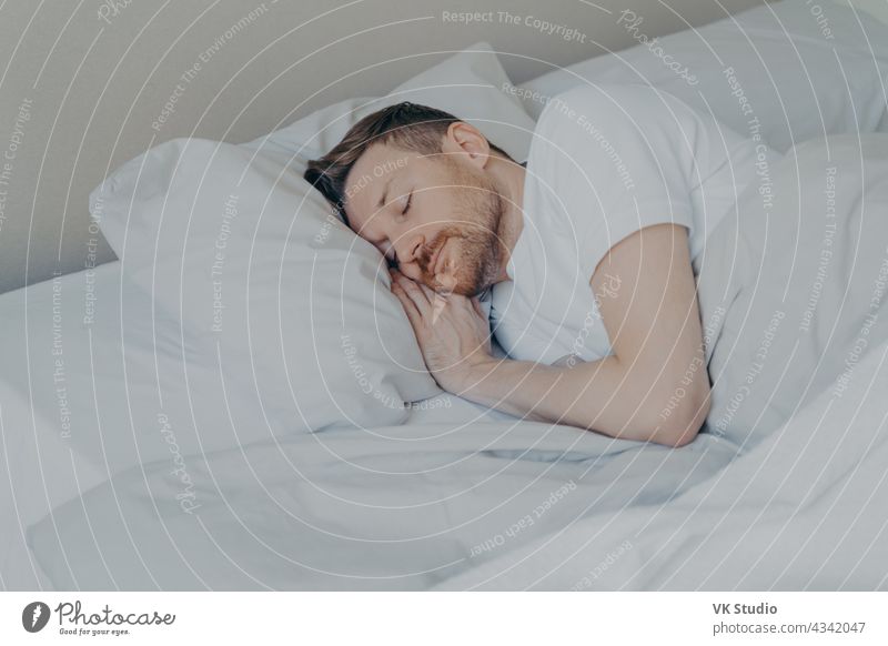 Handsome young man comfortably sleeping in bed at home nap happy handsome bedroom cozy comfortable bedding relax peaceful asleep indoors lying lifestyle pillow