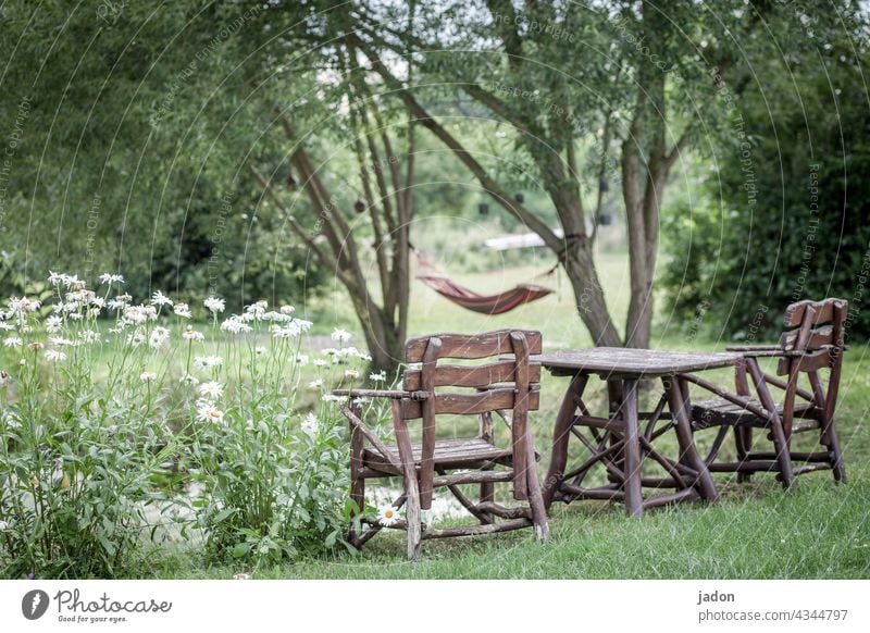 comfort zone. seating group Wooden table Wooden chair wooden furniture Nature flowers Hammock rest chill Shore of a pond trees Summer Exterior shot Break
