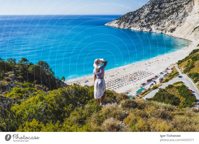 Happy woman standing on top of a rock with hat enjoying Myrtos Beach. Cephalonia island, Greece beach myrtos aerial kefalonia beautiful greece view bay water