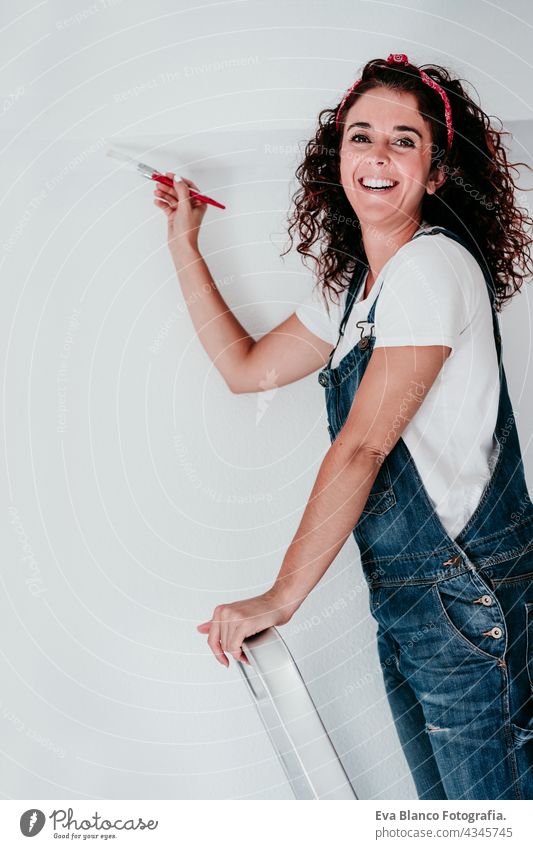 happy caucasian woman painting the room walls with white color. Do it yourself and new home concept house brush young new house painter bricolage solo working