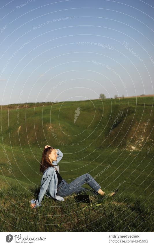 Young woman is sitting on green grass hills and feeling relax on summer sunny day mountain young agriculture people plant road savannah scenery scenic sky
