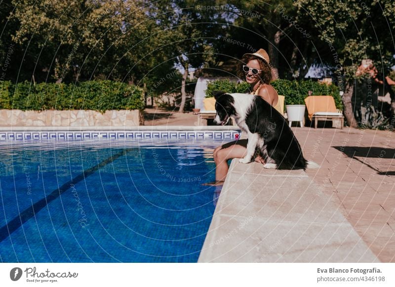 young caucasian woman sitting by pool side with cute border collie dog. Summer time, vacation and lifestyle swimming pool summer together love owner blue water