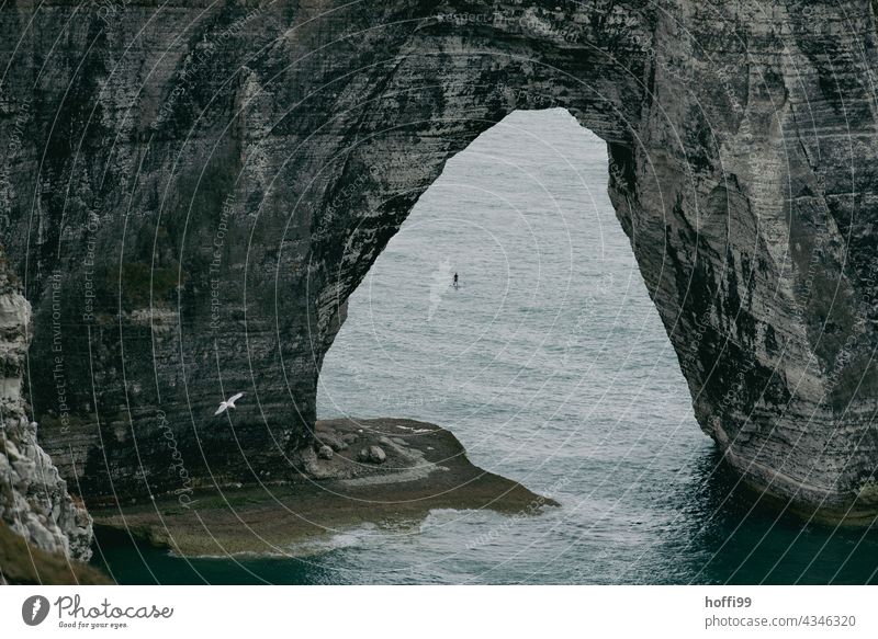 The arch in the sea with standup paddler at Etretat. rock bridge natural arches Rocky coastline Étretat Ocean stand-up paddling