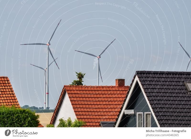 Wind turbines and residential buildings windmills Wind energy plant Renewable energy Technology Energy industry Electricity stream sustainability Sky Clouds Sun