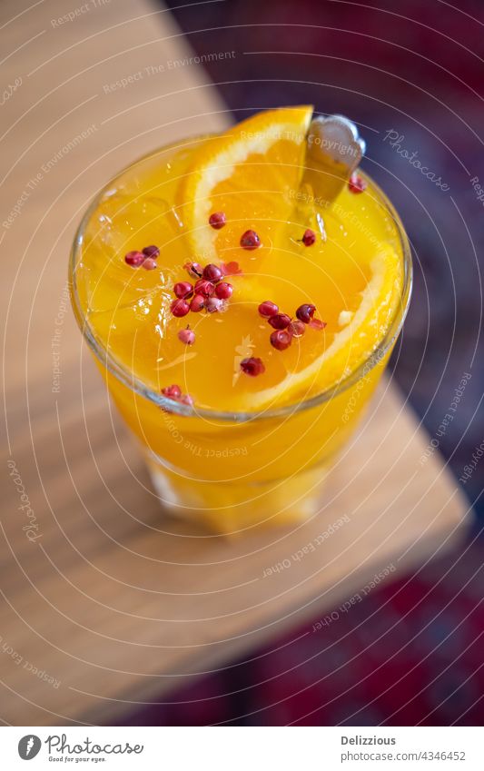 Close-up of a tasty drink with turmeric, honey, ginger and orange topped with pink pepper corns yellow photography pink peppercorns sliced slices fresh
