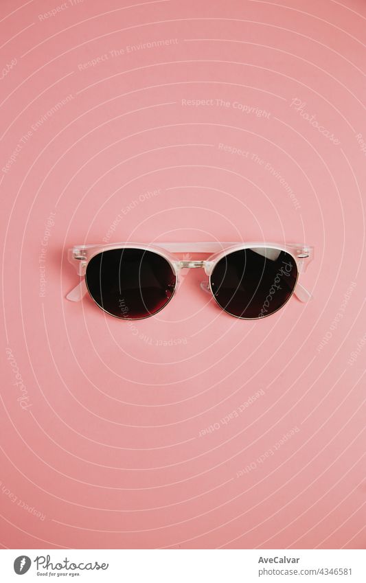 Minimalistic shot of a pair of sunglasses over a pastel pink background with copy space, design and summer concepts minimal tropical trendy female days glamour