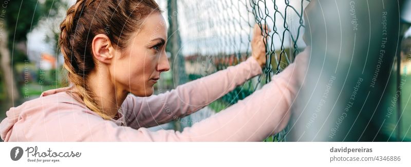 Serious portswoman with boxer braids leaning on a metal fence serious sportswoman profile banner web header panorama panoramic background copy space girl power