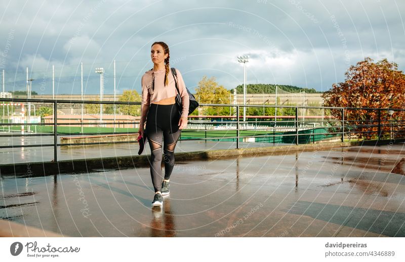 Sportswoman with gym bag and sports shoes walking to go to training sportswoman athlete sports bag sneakers copy space wet floor rainy morning fitness active