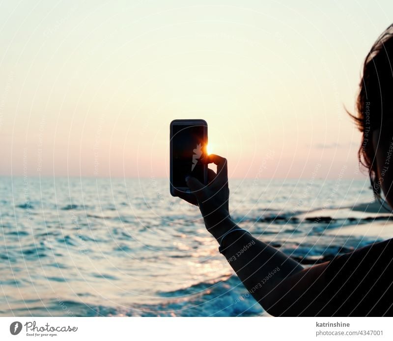 Woman takes a sunset photo on the mobile phone hand close up taking photo beach sea Landscapeб Mobile mobile blue Holding Faceless copy space Sky Communication