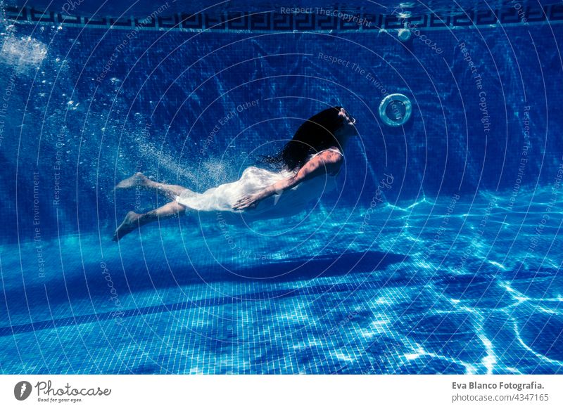 caucasian woman diving in swimming pool wearing white dress.underwater view. Summer time and vacation concept fun summer love blue water sunny day outdoors