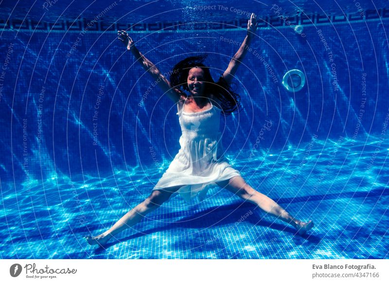caucasian woman diving in swimming pool wearing white dress.underwater view. Summer time and vacation concept fun summer love blue water sunny day outdoors