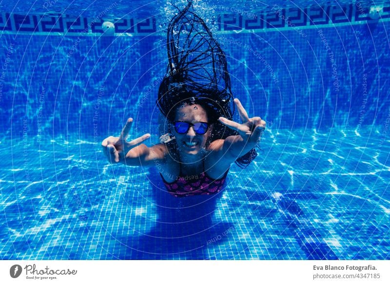 happy caucasian woman wearing sunglasses diving in swimming pool. underwater view. making V sign. Summer time and vacation concept fun summer love blue water