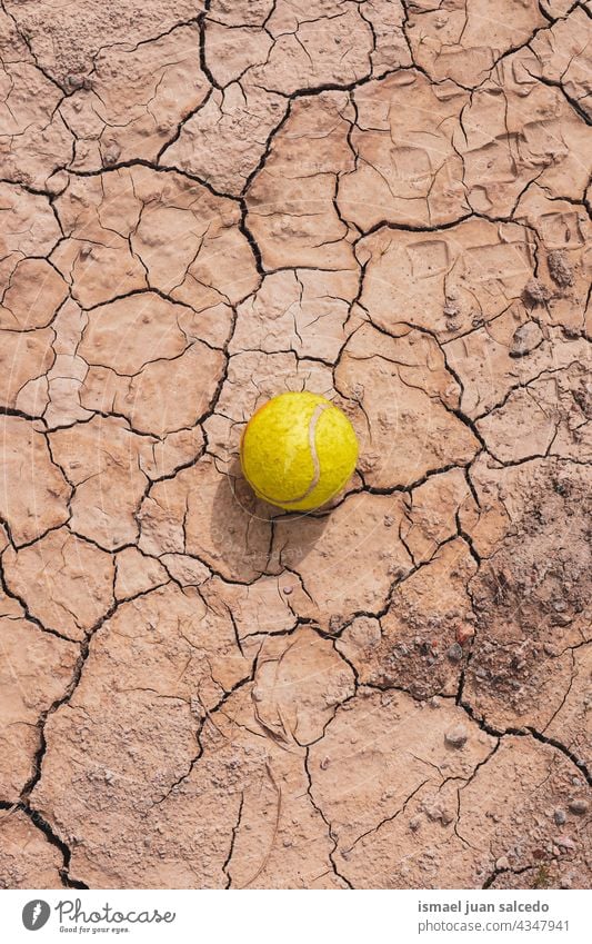 yellow tennis ball on the dessert ground sport object still life brown old abandoned land dry textured earth nature desert climate pattern dirt arid sand