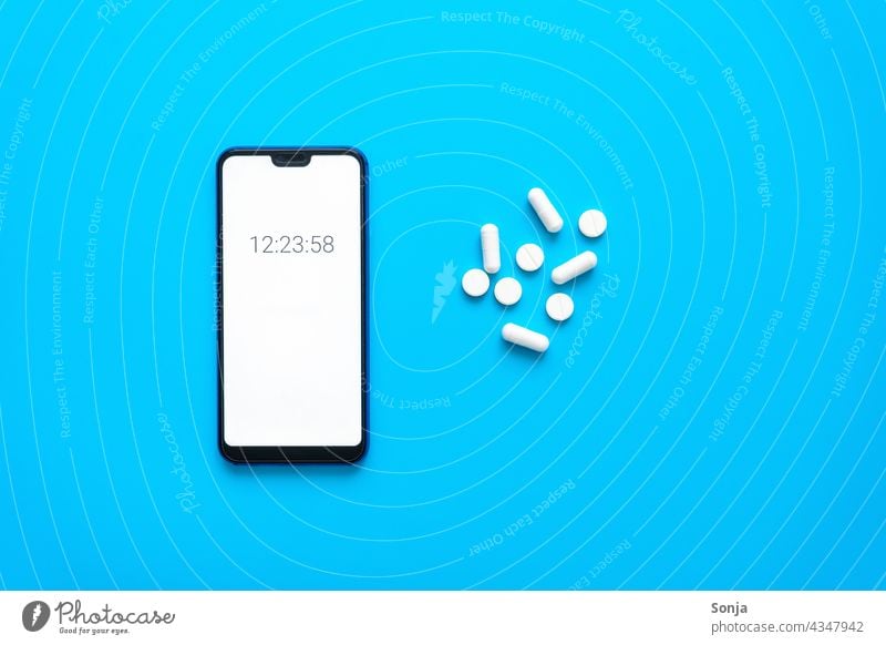 Smartphone with time and white tablets on a blue background. Top view. smartphone Time Pill White Memory timer Screen Telephone Equipment Blue background plan
