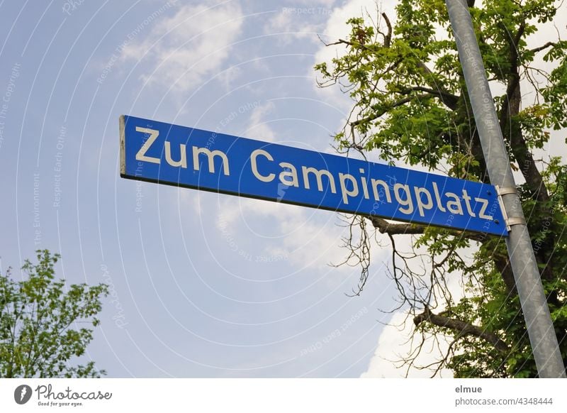 Street name sign " Zum Campingplatz " on an iron bar in front of a tree / live To the camping site street name street sign address Orientation dwell Street sign