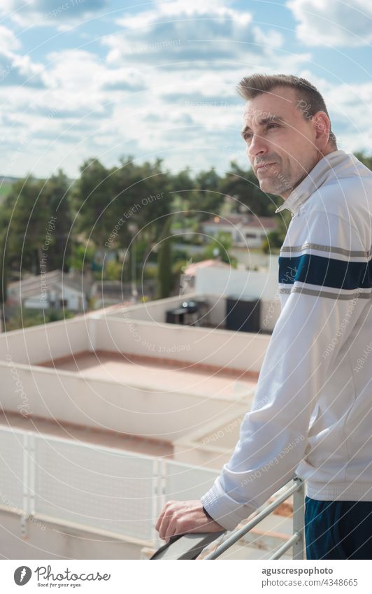 An attractive adult Caucasian man looking at the horizon from a balcony with the sky out of focus in the background. vertical photo male handsome carefree