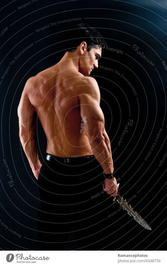 The sexy warrior holds a sword. striking handsome muscle muscular barbarian spartan prince soldier statuesque brave confident fierce lust love spooky ripped