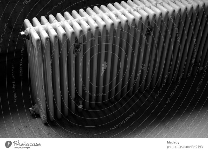 Radiator of a discarded heating system in the darkness of an old cellar in a farmhouse in Rudersau near Rottenbuch in the district of Weilheim-Schongau in Upper Bavaria, photographed in traditional black and white