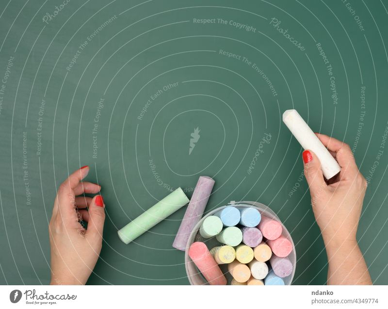 hand holds a piece of white chalk on the background of an empty green chalk board adult advertisement blank caucasian chalkboard childhood classroom closeup