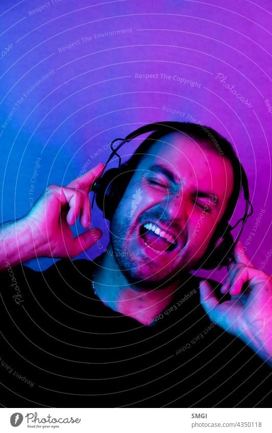 Neon portrait of a caucasian man wearing sunglasses and with headphones listening to music. Listen to music person studio male guy technology model audio sound