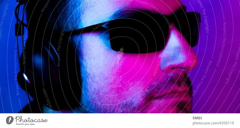 Neon portrait of a caucasian man wearing sunglasses and with headphones listening to music. Listen to music person studio male guy technology model audio sound