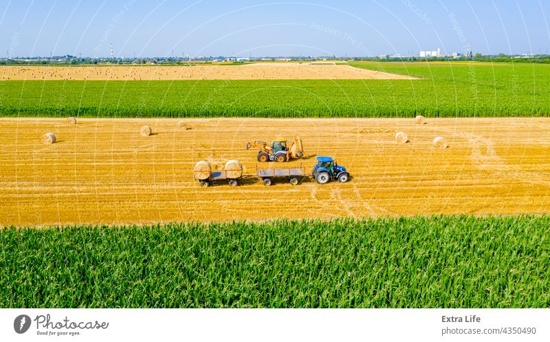 Above view of agricultural field, collecting round bales of straw Aerial Agricultural Agriculture Bale Cargo Carry Cereal Covered Enveloped Excavator Farmer