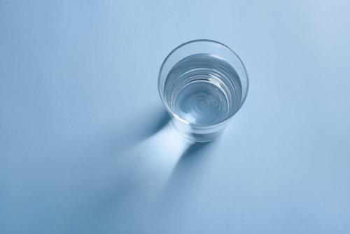 Top view of a glass of clean drinking water on blue background clear top view minimalist beverage liquid transparent reflection purity crystal healthy fresh